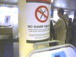 A warning that sharp objects are not permitted on the plane